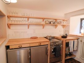 A kitchen with a refrigerator, oven, and shelving at Hole House in Branscombe