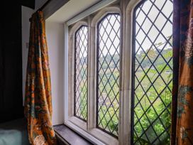 A window with stained glass and floral curtains at Hole House in Branscombe