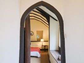 A bedroom with a bed and lamp viewed through an archway at Hole House in Branscombe