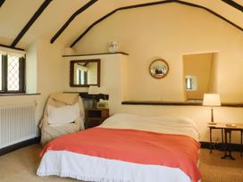 A bedroom with a bed and armchair at Hole House in Branscombe