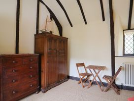 A bedroom with a wardrobe, chest of drawers, table, and chairs at Hole House in Branscombe