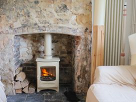 A living room with a wood stove and stone wall at Hole House in Branscombe