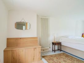 A bedroom with a bed, mirror, and side table at Hole House in Branscombe
