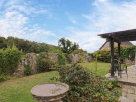 A garden with a bird bath and stone wall at Hole House in Branscombe