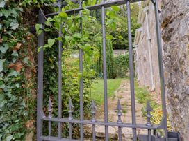 A garden with a gate and stone wall at Hole House in Branscombe