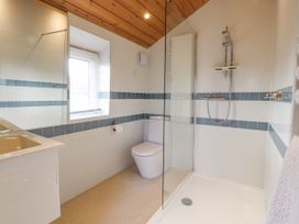A bathroom with a shower area a toilet a sink a window and wooden ceiling at Artisan Lodge in Longridge