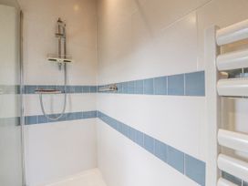 A shower area with blue and white tiled walls and a chrome showerhead at Artisan Lodge in Longridge