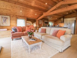 A living room with two sofas a wooden coffee table with flowers and a kitchen area at Artisan Lodge in Longridge