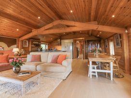 An open living and dining area with beige sofa and wooden dining table at Artisan Lodge in Longridge