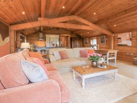 A living room with wooden ceiling and walls with two sofas and a wooden coffee table with flowers at Artisan Lodge in Longridge