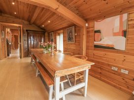 A wooden dining room with a long table bench and chairs and paintings on the walls at Artisan Lodge in Longridge