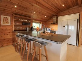 A kitchen with a countertop island and stools inside a wooden cabin at Artisan Lodge in Longridge