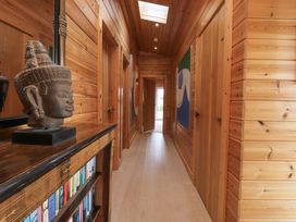 A wooden hallway with a bookshelf and statue on the left and paintings on the walls at Artisan Lodge in Longridge