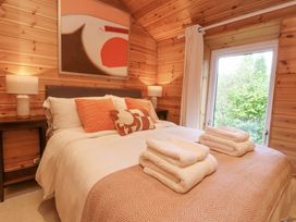 A bedroom with a bed with pillows and folded towels and wooden walls at Artisan Lodge in Longridge