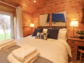 A bedroom with a bed with white and blue pillows towels on the bed wooden desk with a plant and lamp Artisan Lodge Longridge