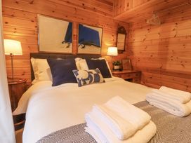 A bedroom with a bed with white and blue pillows and folded towels on a blanket at Artisan Lodge in Longridge