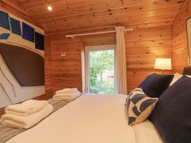A bedroom with wooden walls a window with curtains a bed with pillows and folded towels and a bedside lamp at Artisan Lodge in Longridge