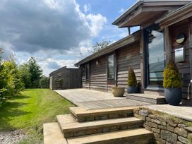An exterior view of a wooden house with steps leading to a wooden deck and plants in pots at Artisan Lodge in Longridge