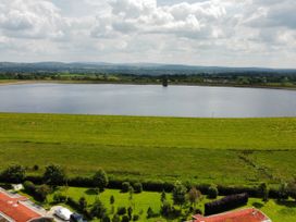 A large water reservoir surrounded by green fields and trees with buildings in the foreground at Artisan Lodge in Longridge