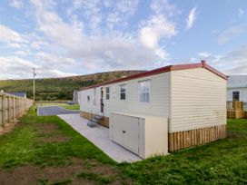 A single wide caravan on grass with a small set of stairs and a storage box outside at Meric Stone Holiday lets Caravan 1 in Benone near Castlerock