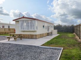 An exterior view of a caravan with a gravel driveway a wooden picnic table and grass at Meric Stone Holiday lets Caravan 1 in Benone near Castlerock
