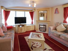 A living room with two sofas a coffee table a television on a cabinet and a fireplace at Meric Stone Holiday lets Caravan 1 in Benone near Castlerock