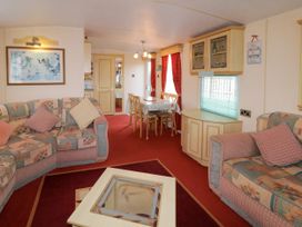 A living room and dining area with sofas, a coffee table, a dining table with chairs, and cabinets at Meric Stone Holiday lets Caravan 1 in Benone near Castlerock