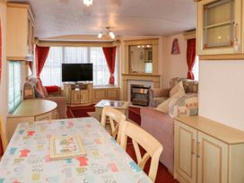 A living room with sofas a television a fireplace and a dining table with chairs at Meric Stone Holiday lets Caravan 1 Benone near Castlerock