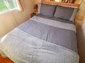 A bedroom with a double bed covered with gray bedding and a white knitted throw in Meric Stone Holiday lets Caravan 1 Benone near Castlerock