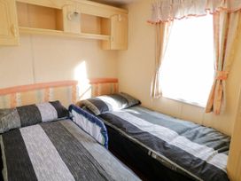 A bedroom with two single beds and a window with curtains at Meric Stone Holiday lets Caravan 1 Benone near Castlerock