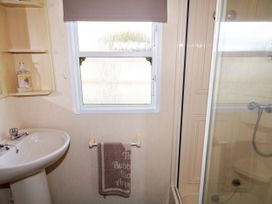 A bathroom with a sink soap dispenser towel on a rack window and shower at Meric Stone Holiday lets Caravan 1 Benone near Castlerock