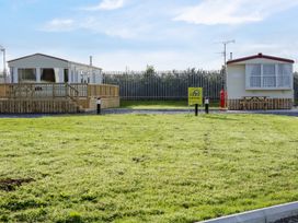 Two caravans with wooden decking and picnic table on a grass area at Meric Stone Holiday lets Caravan 1 Benone near Castlerock