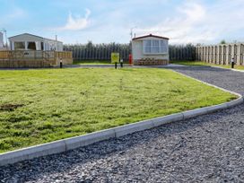 A gravel driveway with grass lawns and two caravans fenced on the sides at Meric Stone Holiday lets Caravan 1 Benone near Castlerock