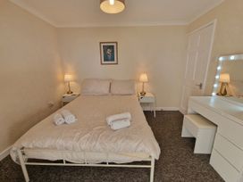 A bedroom with a bed and dresser at Woodland Roost in Barmouth
