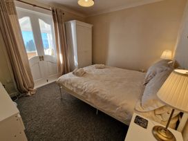 A bedroom with a bed and wardrobe at Woodland Roost in Barmouth
