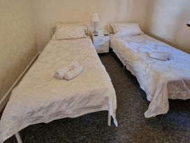 A bedroom with two single beds and a nightstand at Woodland Roost in Barmouth