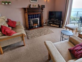 A living room with a fireplace and television at Woodland Roost in Barmouth