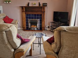A living room with a fireplace and seating at Woodland Roost in Barmouth