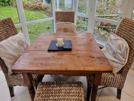A table with chairs and a candle in the conservatory at Woodland Roost in Barmouth