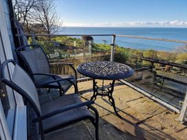 A balcony with table and chairs overlooking the sea at Woodland Roost in Barmouth