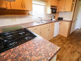 A kitchen with a gas stove sink microwave kettle and cupboards at Meric Stone Holiday Lets Caravan 2 Benone near Castlerock