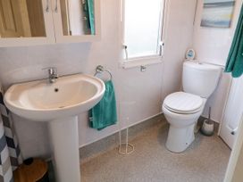 A bathroom with a pedestal sink toilet mirror cabinet green towel and window at Meric Stone Holiday Lets Caravan 2 Benone near Castlerock