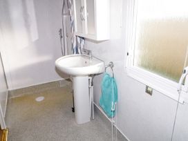 A bathroom with a pedestal sink shower and a towel hanging next to a window at Meric Stone Holiday Lets Caravan 2 in Benone near Castlerock