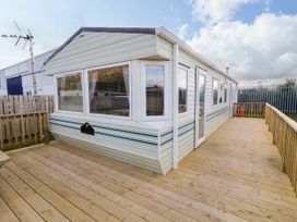 A caravan with large windows and a wooden deck surrounding it at Meric Stone Holiday Lets Caravan 2 in Benone near Castlerock