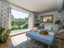 A living room with a large window overlooking greenery a striped ottoman and a sofa at Holly Cottage in Llechwedd near Conwy