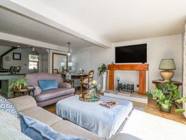 A living room with sofas a coffee table a fireplace a television and plants at Holly Cottage in Llechwedd near Conwy