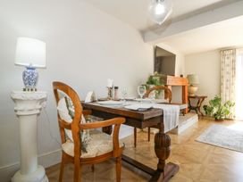 A dining area with a wooden table set with plates and glasses two wooden chairs and lamps at Holly Cottage in Llechwedd near Conwy