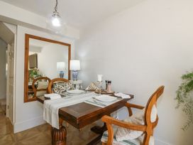 A dining table set for two with wooden chairs a large mirror on the wall and a lamp on a side table at Holly Cottage in Llechwedd near Conwy