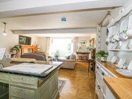 A living room and kitchen area with sofas plants and dishes on shelves at Holly Cottage in Llechwedd near Conwy
