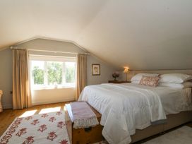 A bedroom with a bed a wooden chest a window with curtains and a side table with a lamp at Holly Cottage in Llechwedd near Conwy